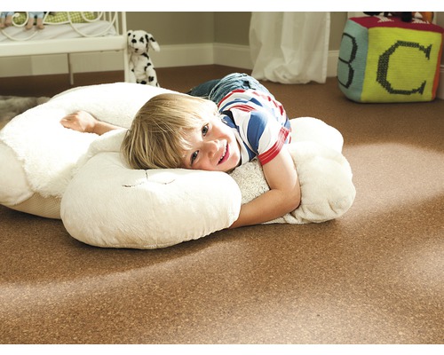 Junge liegt auf dem Korkboden im Kinderzimmer