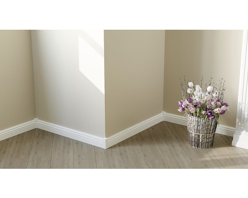 Coin de pièce avec sol stratifié, plinthes décoratives blanches et composition florale