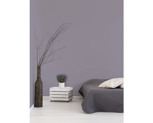 Chambre avec lit, caisse en bois sur roulettes comme table de chevet, vase et décoration