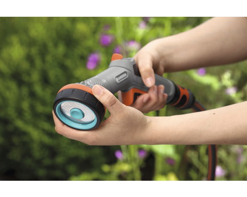 Une personne tient une lance d''arrosage multijets Gardena à la main pour arroser.