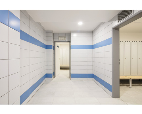 Couloir avec murs carrelés et vestiaire en arrière-plan