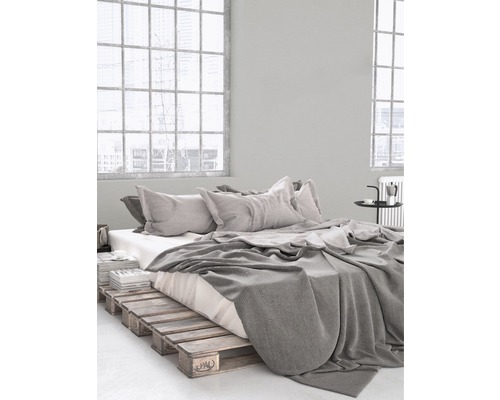 Chambre avec cadre de lit en palettes de bois, literie et coussins