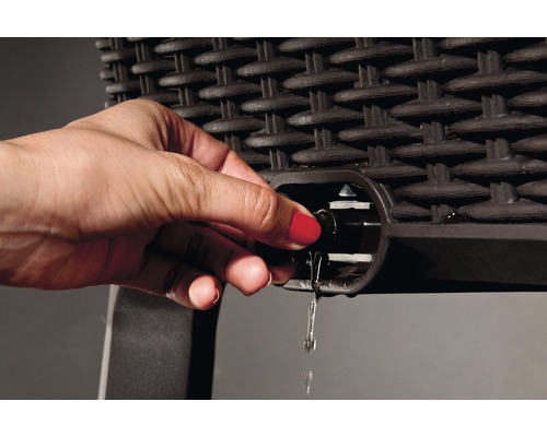Eine Hand öffnet den Wasserablauf eines Rattanmöbelstücks