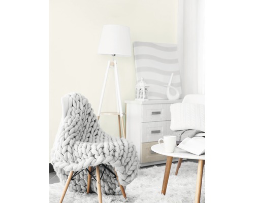 Wohnzimmer-Szene mit Sessel, Strickdecke, Stehlampe, Beistelltisch und Kommode