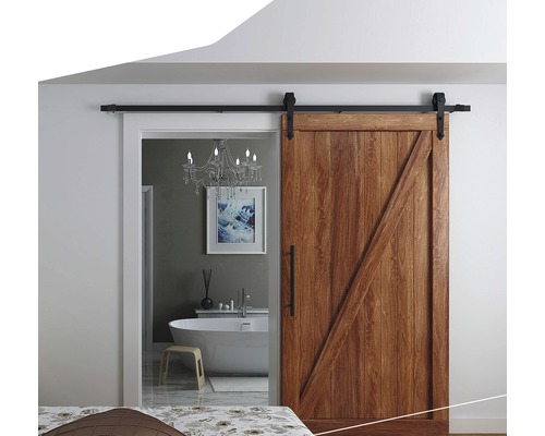 Porte coulissante en bois devant une salle de bains avec baignoire et lustre