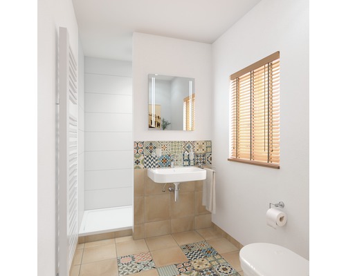 Salle de bain lumineuse avec lavabo, miroir, radiateur et carrelage à motifs.