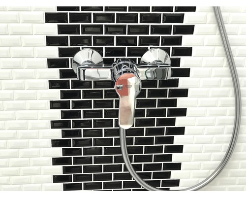 Robinet de douche devant un mur de carreaux noirs et blancs