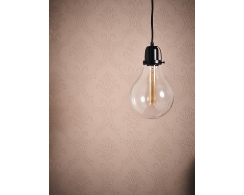 Ampoule décorative en verre transparent devant un mur à motifs floraux