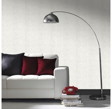 Salon avec canapé blanc, coussins, lampadaire et papier peint à motifs