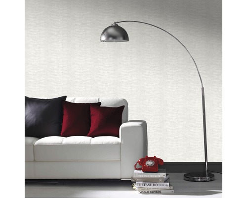 Salon avec canapé blanc, coussins, lampadaire et papier peint à motifs