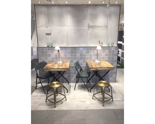 Salle d''exposition avec deux tables et des sièges, fond carrelé et éclairage.