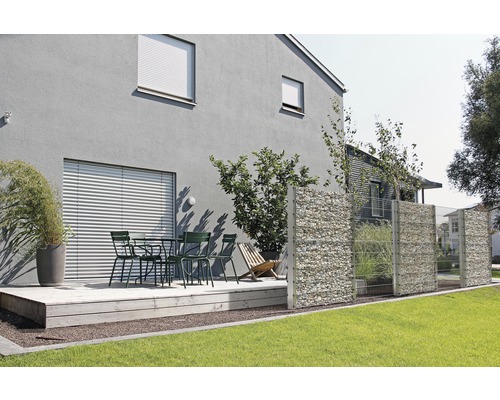 Jardin avec clôture de gabions, terrasse et coin salon devant une maison