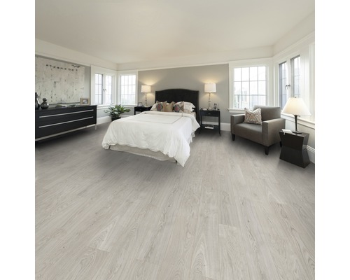 Chambre claire avec lit, commode, fauteuil et plancher en bois clair