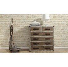 Commode avec six tiroirs, lampe et paniers décoratifs devant un mur de briques
