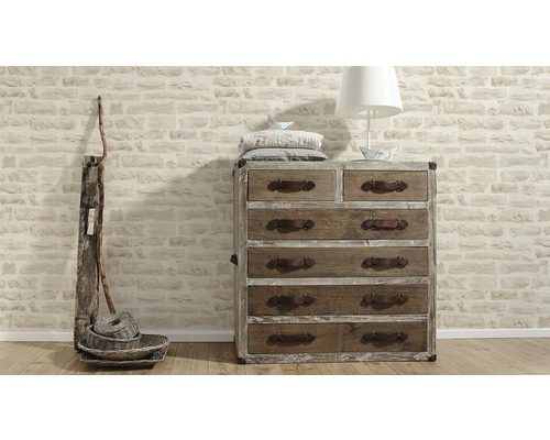 Kommode mit Schubladen, Lampe, Kissen und Dekoration vor einer Steinwand