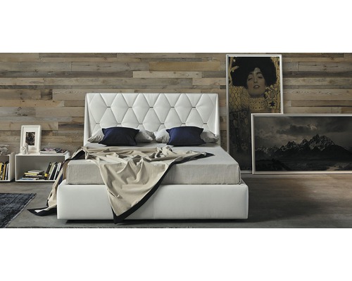 Lit avec tête de lit matelassée, table de chevet et tableaux dans la chambre