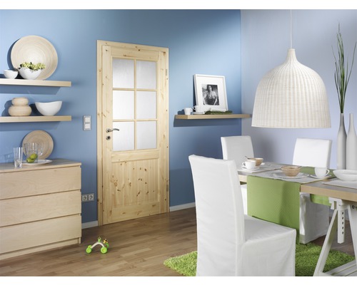 Salon lumineux avec porte en bois, table à manger et chaises