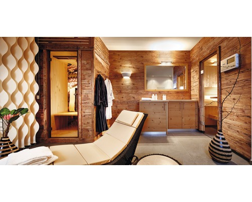 Holzvertäfelter Wellnessbereich mit Liege, Bademänteln, Waschtisch und Sauna