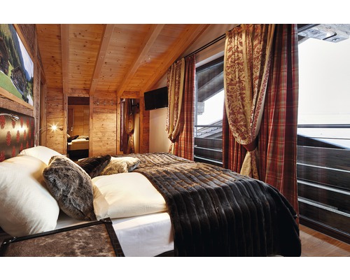 Schlafzimmer mit Holzwänden, Bett und Vorhängen
