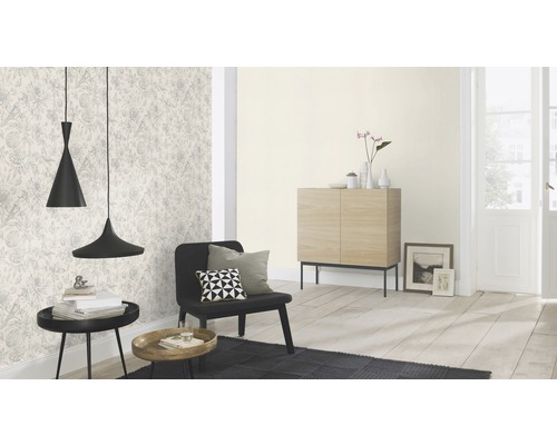 Wohnzimmer mit gemusterter Tapete, schwarzem Sessel und zwei Pendelleuchten