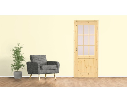Porte en bois clair avec insert en verre à côté d''un fauteuil gris et d''une plante d''intérieur