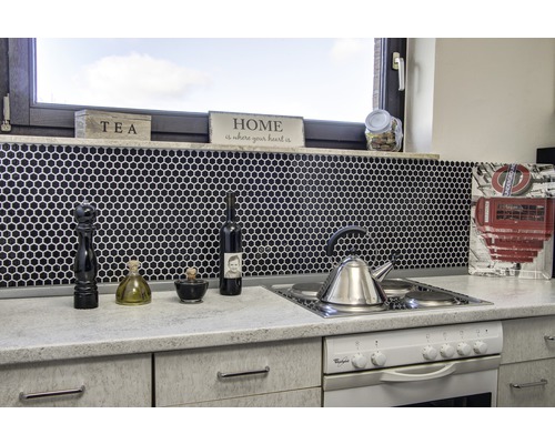 Scène de cuisine avec évier, cuisinière, robinetterie et ustensiles de cuisine sur fond de mosaïque noire