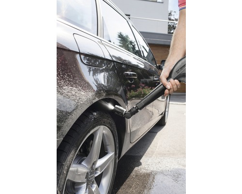 Une personne nettoie une voiture avec un nettoyeur haute pression.