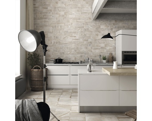 Pièce lumineuse avec kitchenette, carrelée avec des carreaux aspect pierre.
