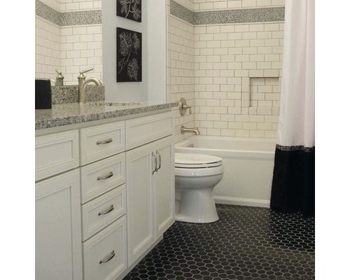 Salle de bain avec carrelage blanc, meuble-lavabo et sol en mosaïque noire.