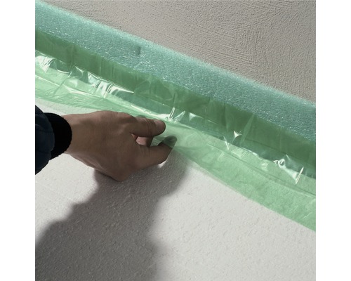 Personne fixant des bandes d''isolation de rive à un mur