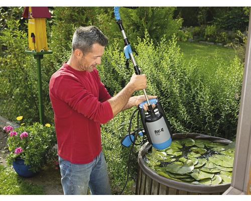 Mann bedient eine Teichpumpe von for_q in einem Gartenteich