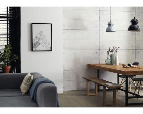 Salon avec canapé, table à manger, banc et panneaux muraux aspect béton.