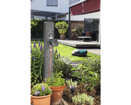 Scène de jardin avec robinet d''eau, système de commande d''irrigation et robot de tonte dans le jardin