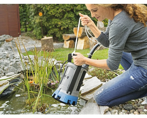 Une femme utilise une pompe à eau sale dans un bassin de jardin