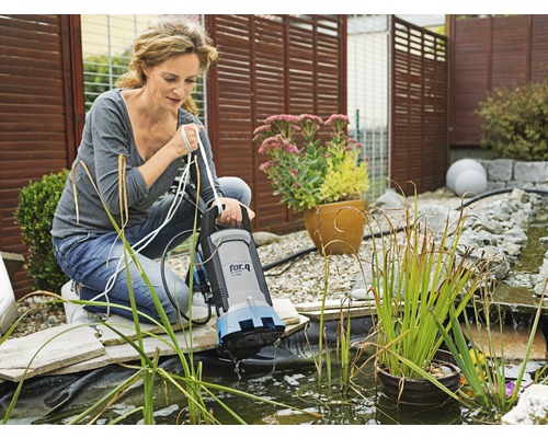 Une femme utilise une pompe de bassin de la marque for.q dans un bassin de jardin.