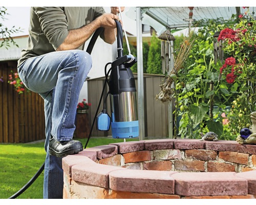 Homme avec pompe submersible dans un puits de jardin
