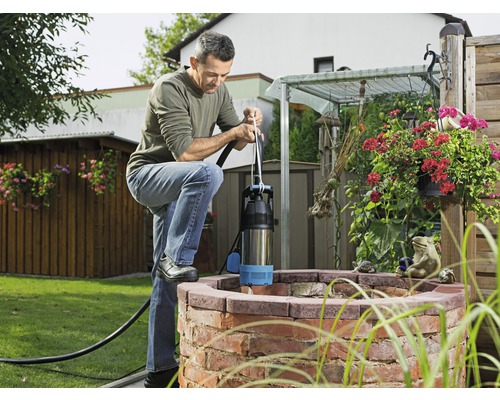 Un homme utilise une pompe de puits profond sur un puits dans le jardin.