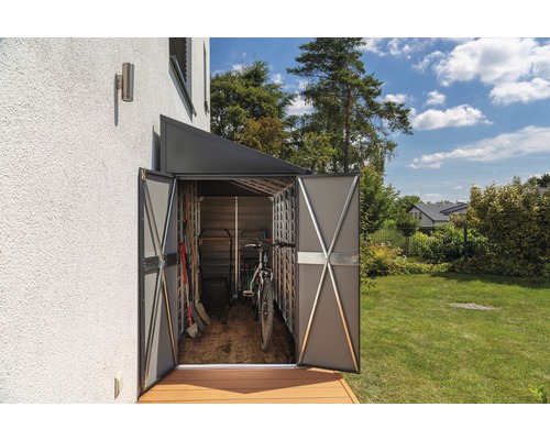 Armoire de jardin en métal avec portes ouvertes contre un mur de maison, contenant des outils de jardin et un vélo