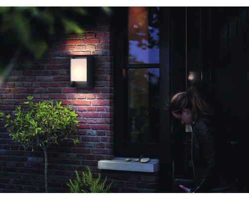 Aussenansicht eines Hauses mit einer beleuchteten Wandleuchte neben einer Tür