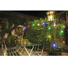 Extérieur avec mobilier de jardin vert, éclairé par une guirlande lumineuse et une lanterne.