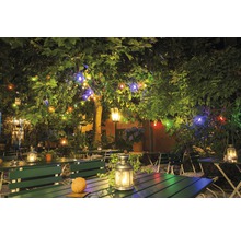 Jardin de restaurant avec tables, bancs et guirlandes lumineuses