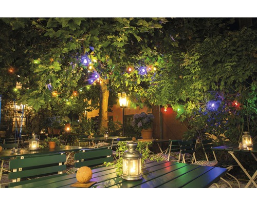 Jardin de restaurant avec tables, bancs et guirlandes lumineuses