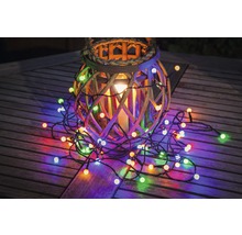 Lanterne décorative en osier avec une guirlande lumineuse multicolore sur une table en bois