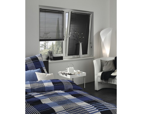 Schlafzimmer mit Fenster, ausgestattet mit schwarzen Jalousien zur Lichtsteuerung.