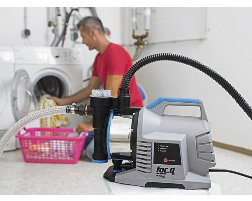 Station de pompage domestique utilisée dans une buanderie avec une personne mettant du linge dans un lave-linge