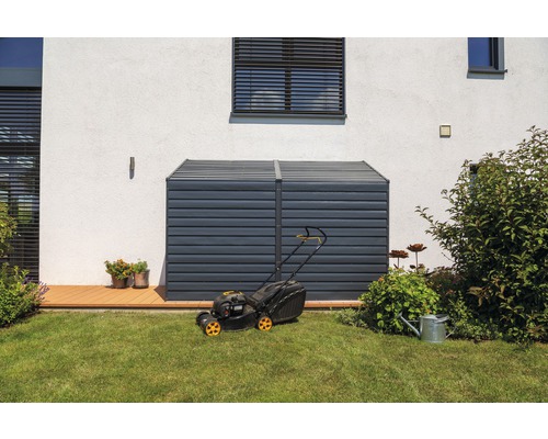 Jardin avec coffre de rangement et tondeuse à gazon devant une maison