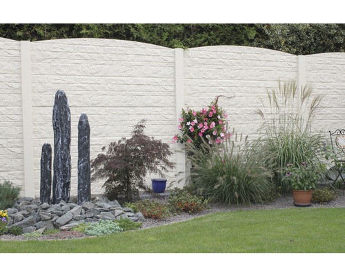 Scène de jardin avec clôture en béton, sculptures en pierre et plantations