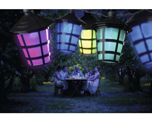 Guirlande lumineuse avec lanternes colorées au-dessus d''une famille assise dans le jardin