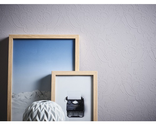 Helle Tapete mit floralem Muster, kombiniert mit dekorativen Rahmen und einer Vase