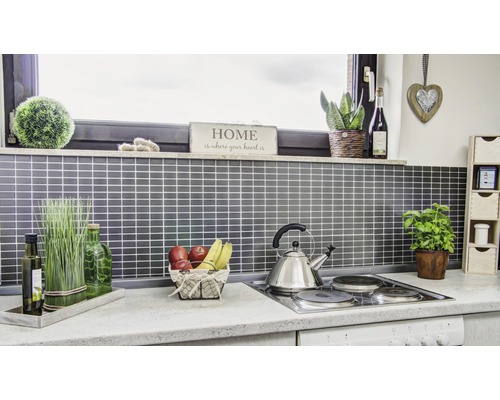 Küchenszene mit Accessoires und Utensilien auf einer Arbeitsfläche vor einer gefliesten Wand